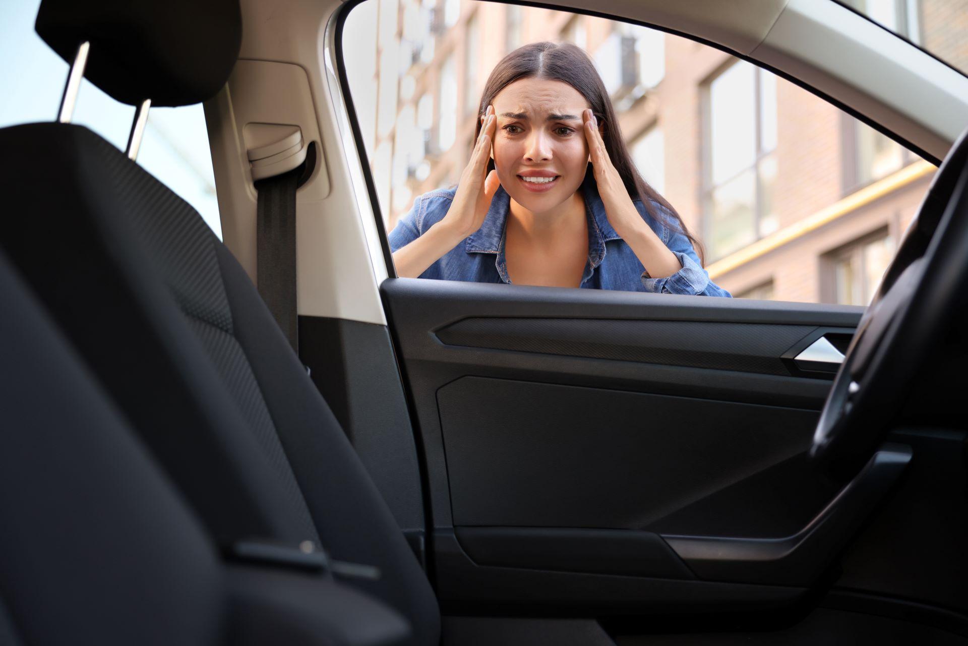 Auto ausgesperrt, Schlüssel drinnen vergessen. Emotionale Frau schaut durch das Autofenster