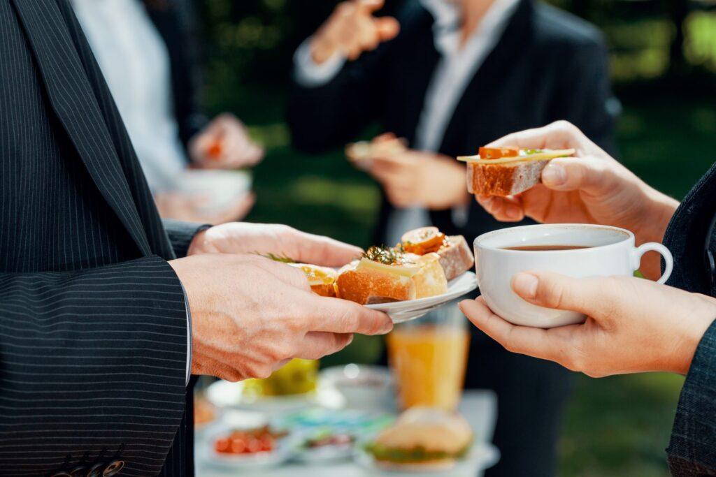 Nahaufnahme von Geschäftsleuten, die während eines Geschäftsessens im Freien Kaffee und belegte Brötchen essen