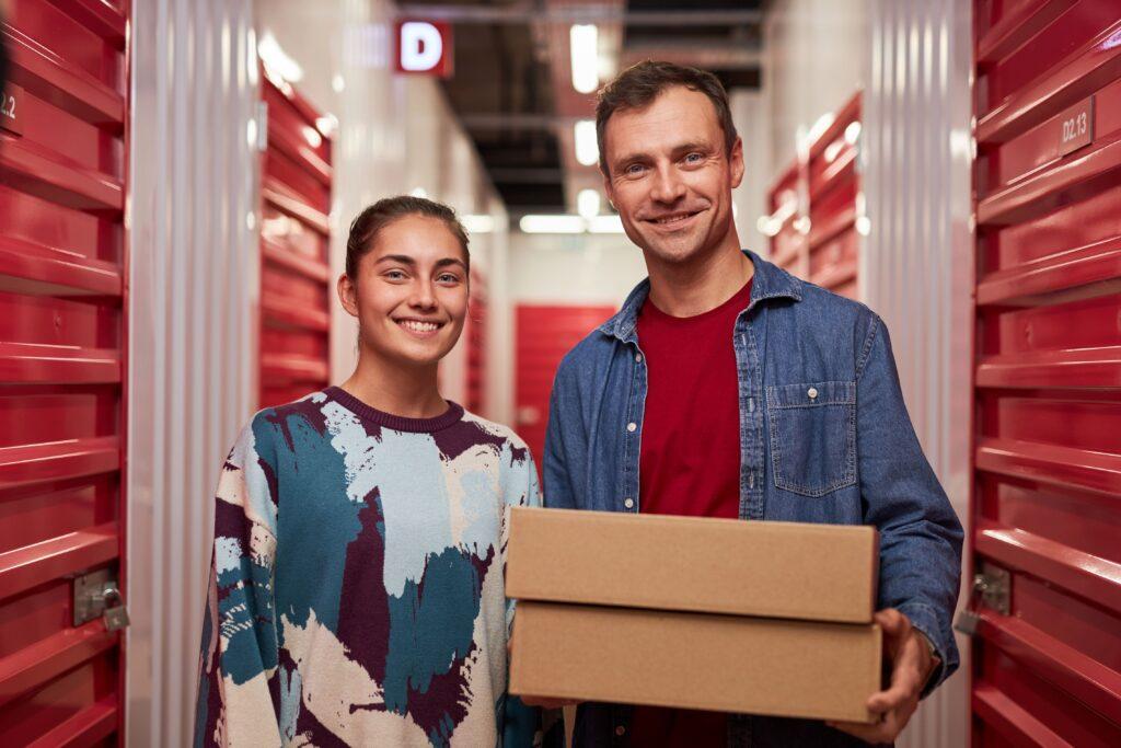 Zwei Personen in einer Self-Storage-Anlage mit roten Lagertüren