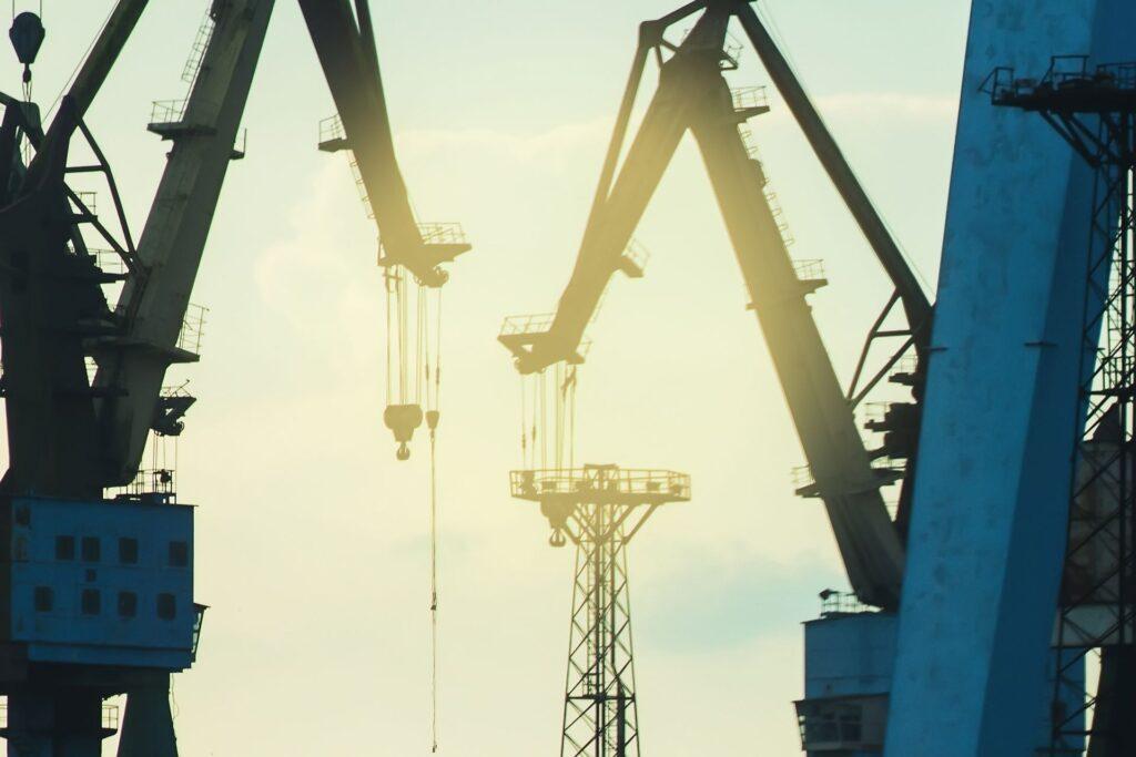 Industriekräne mit Elektrokettenzügen in einem Hafen.