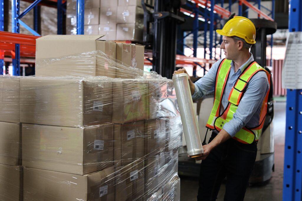 Mitarbeiter verpackt Paletten mit Folie | Schrenzpapier