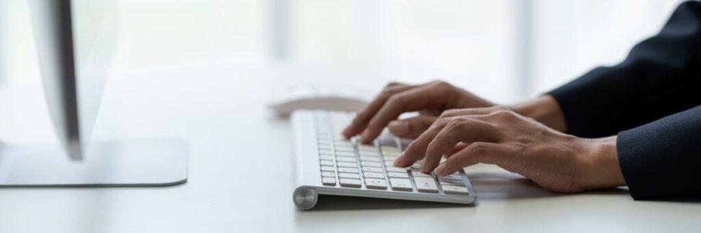 Hände tippen auf einer weißen Tastatur im modernen Buero, Symbolbild fuer digitale Dienstleistungen und transparente Bueroservice Preise