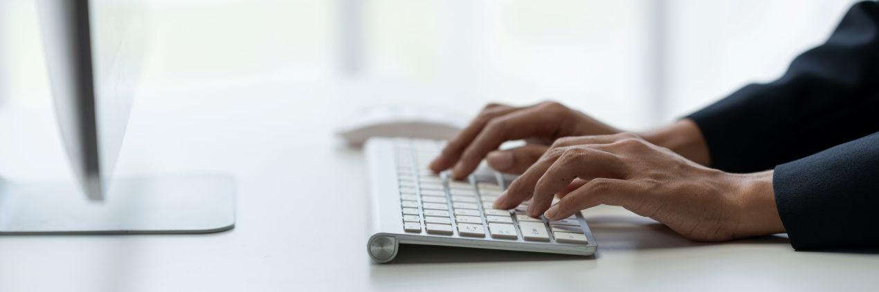 Hände tippen auf einer weißen Tastatur im modernen Buero, Symbolbild fuer digitale Dienstleistungen und transparente Bueroservice Preise