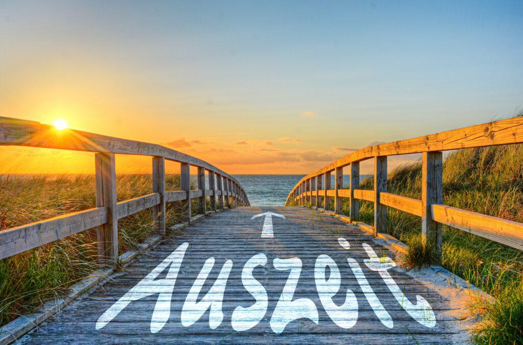 Holzsteg zum Meer im Sonnenuntergang mit Schrift Auszeit | Berghütte Österreich