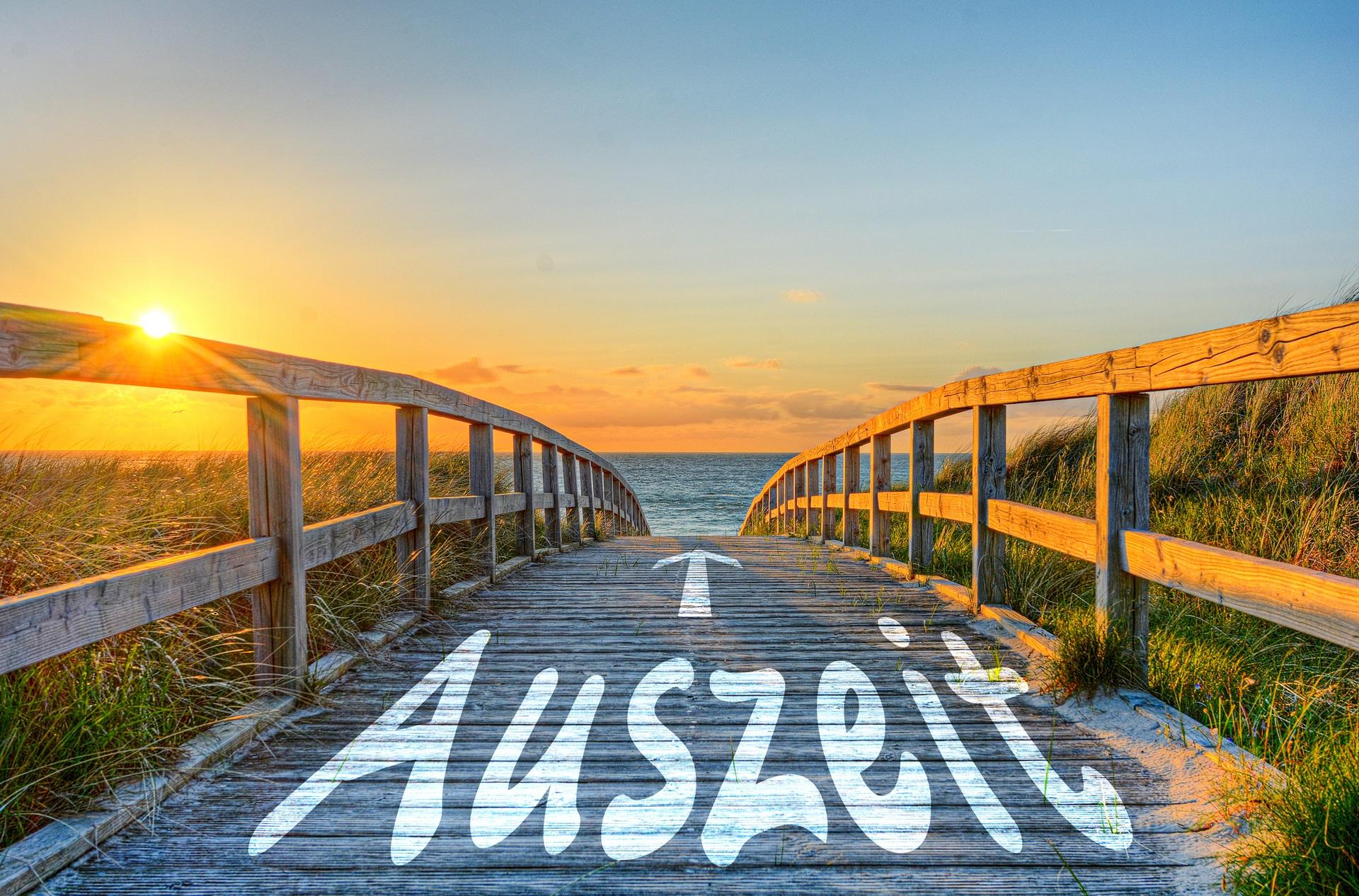 Holzsteg zum Meer im Sonnenuntergang mit Schrift Auszeit | Berghütte Österreich
