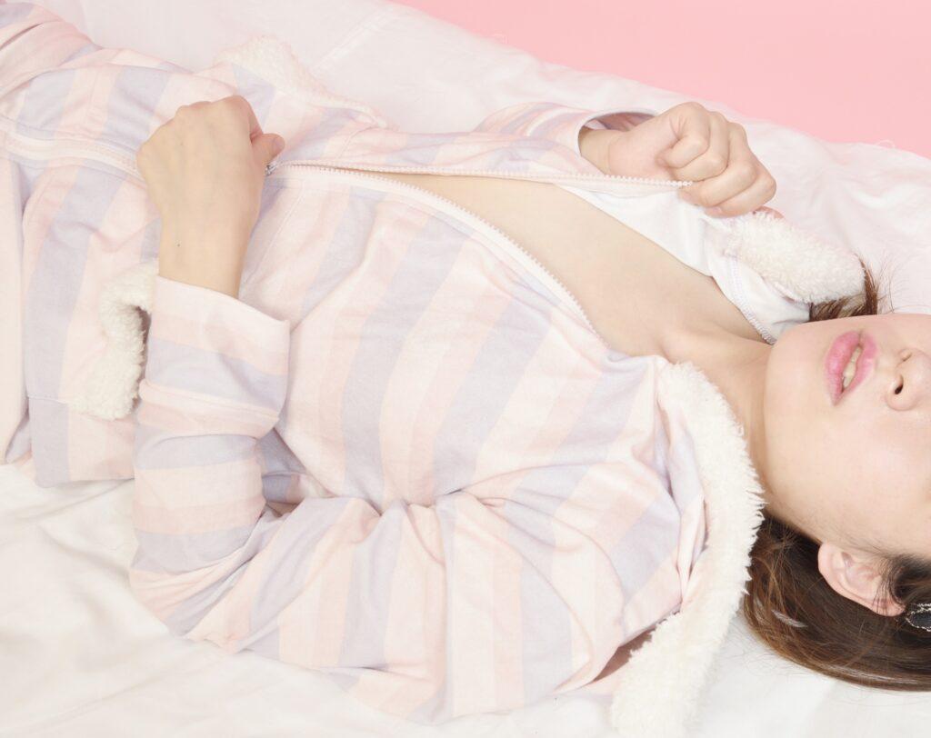 Frau in pastellfarbener Kleidung liegt entspannt auf Bett | Escort werden